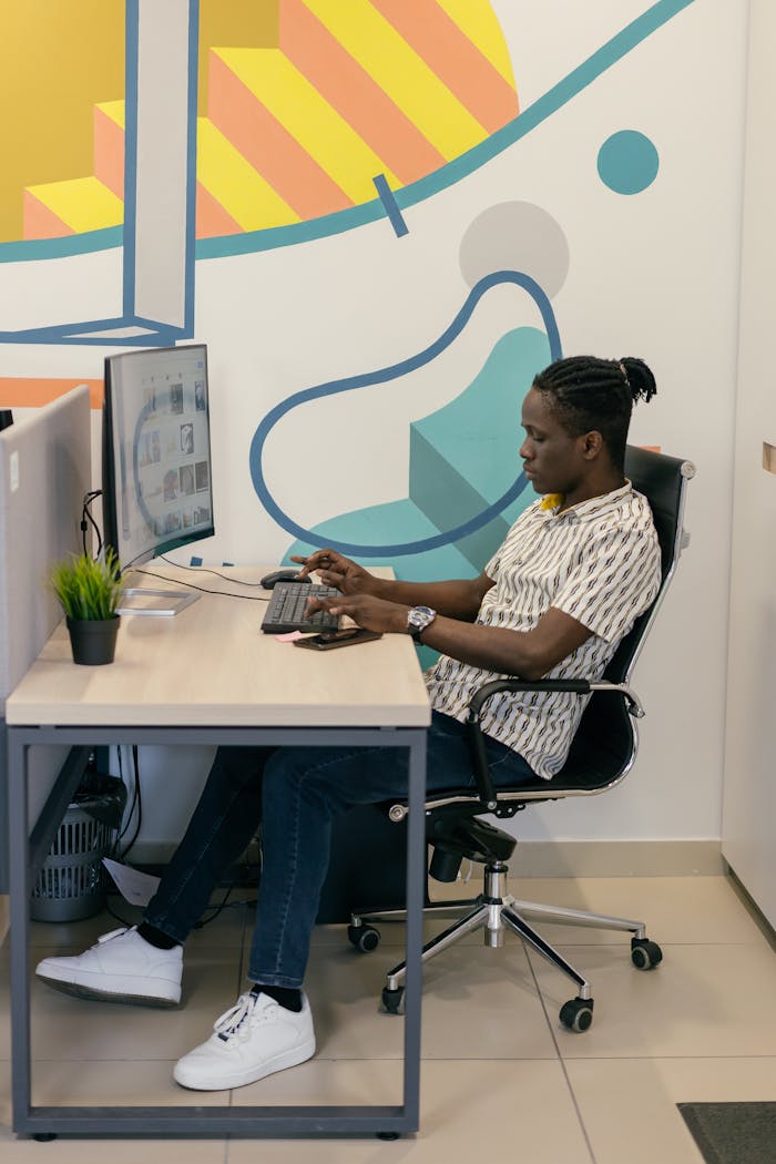 A man working at a computer in a modern office setting, focused on his tasks